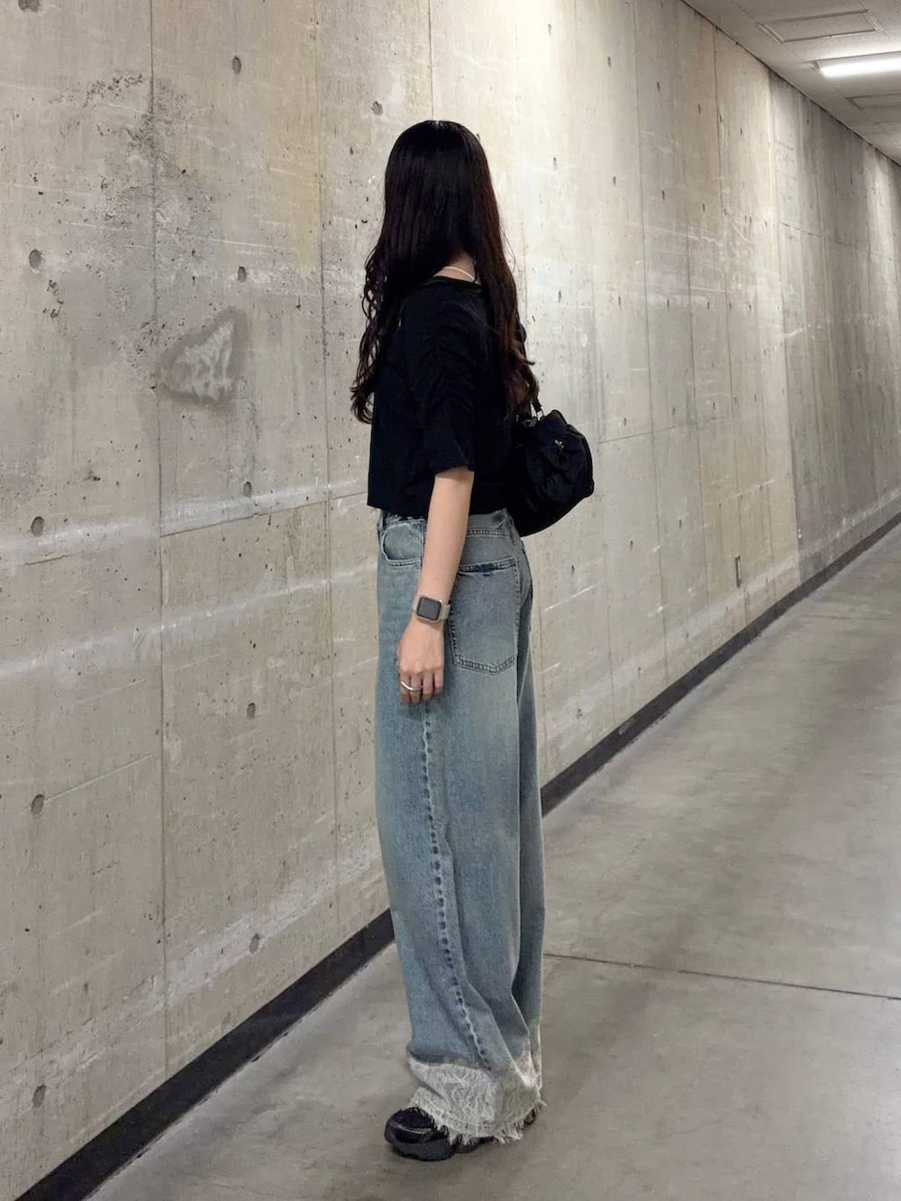 ブルー系のデニムパンツ、ブラック系のTシャツ/カットソー、ブラック系のボストンバッグを着用したレディースの夏コーディネートの2枚目の写真