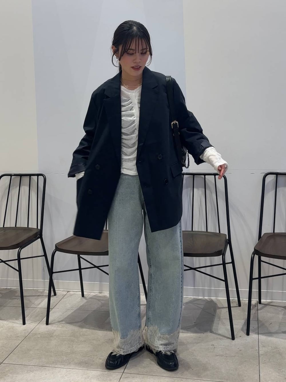 ブルー系のデニムパンツ、ブラック系のショルダーバッグ、ブラック系のローファーを着用したレディースの春コーディネートの5枚目の写真