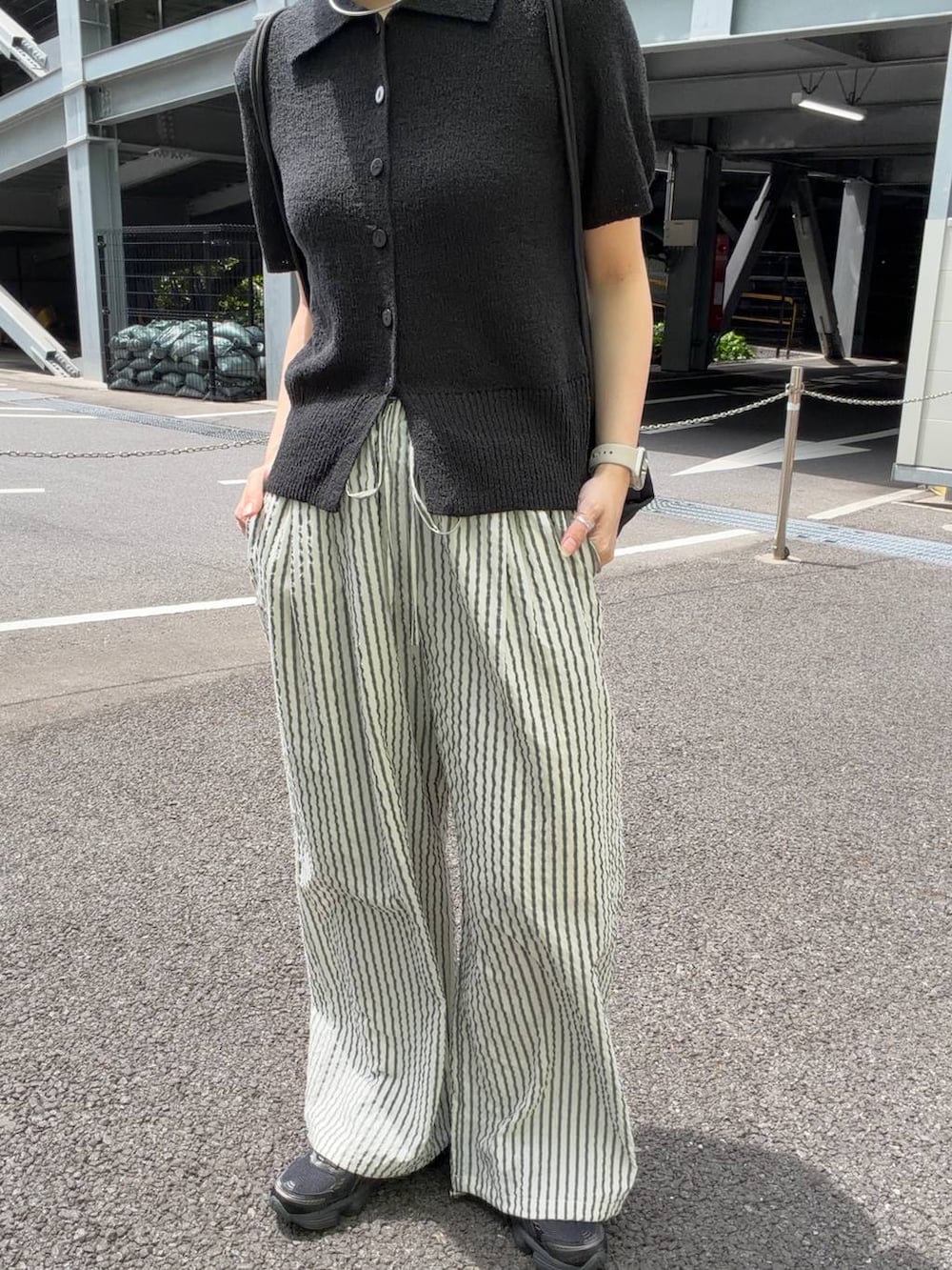 ブラック系のTシャツ/カットソー、ブラック系のバックパック/リュック、ホワイト系のその他パンツを着用したレディースの春コーディネートの2枚目の写真