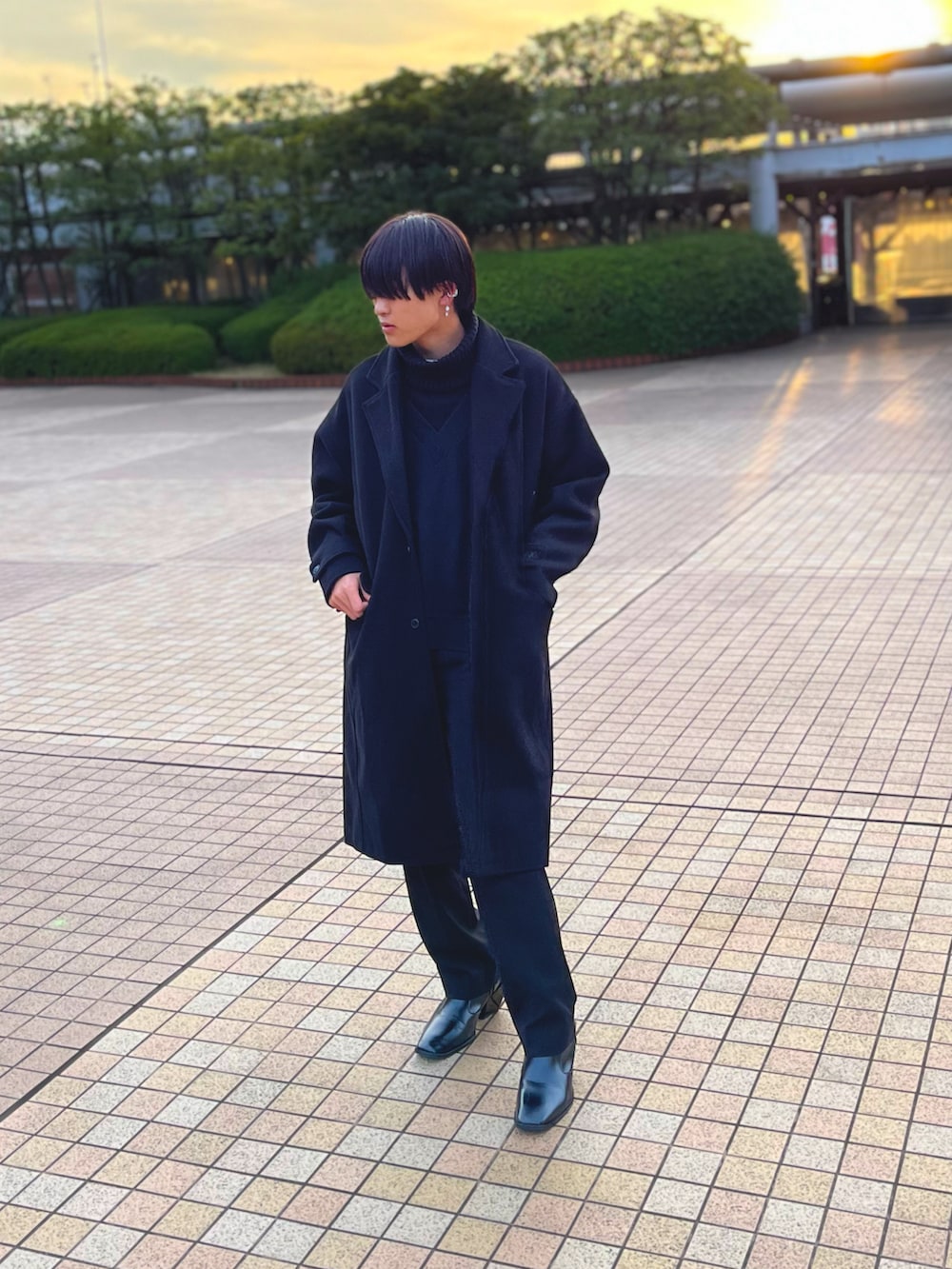 ホワイト系のニット/セーター、ブラック系のチェスターコート、ブラック系のスラックスを着用したメンズの冬コーディネートの3枚目の写真