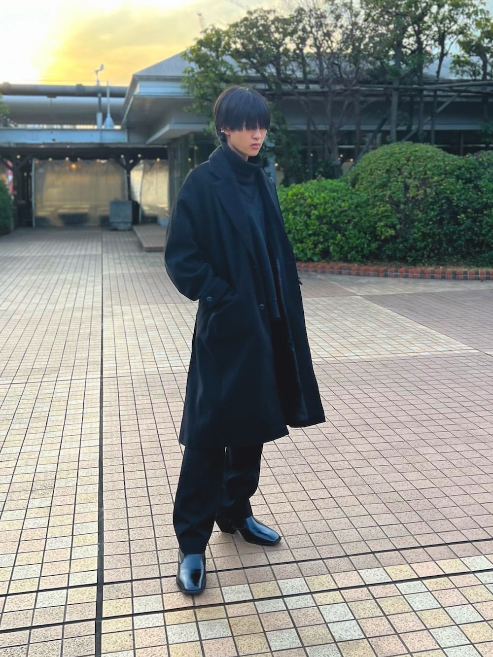 ホワイト系のニット/セーター、ブラック系のチェスターコート、ブラック系のスラックスを着用したメンズの冬コーディネートの2枚目の写真