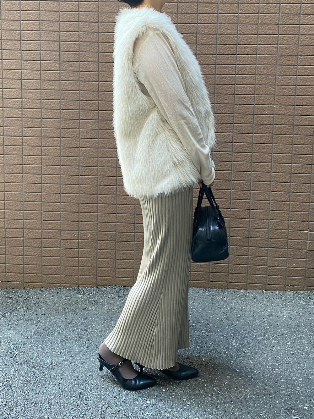 ホワイト系のベスト、ホワイト系のTシャツ/カットソー、ベージュ系のスカートを着用したレディースの秋コーディネートの2枚目の写真