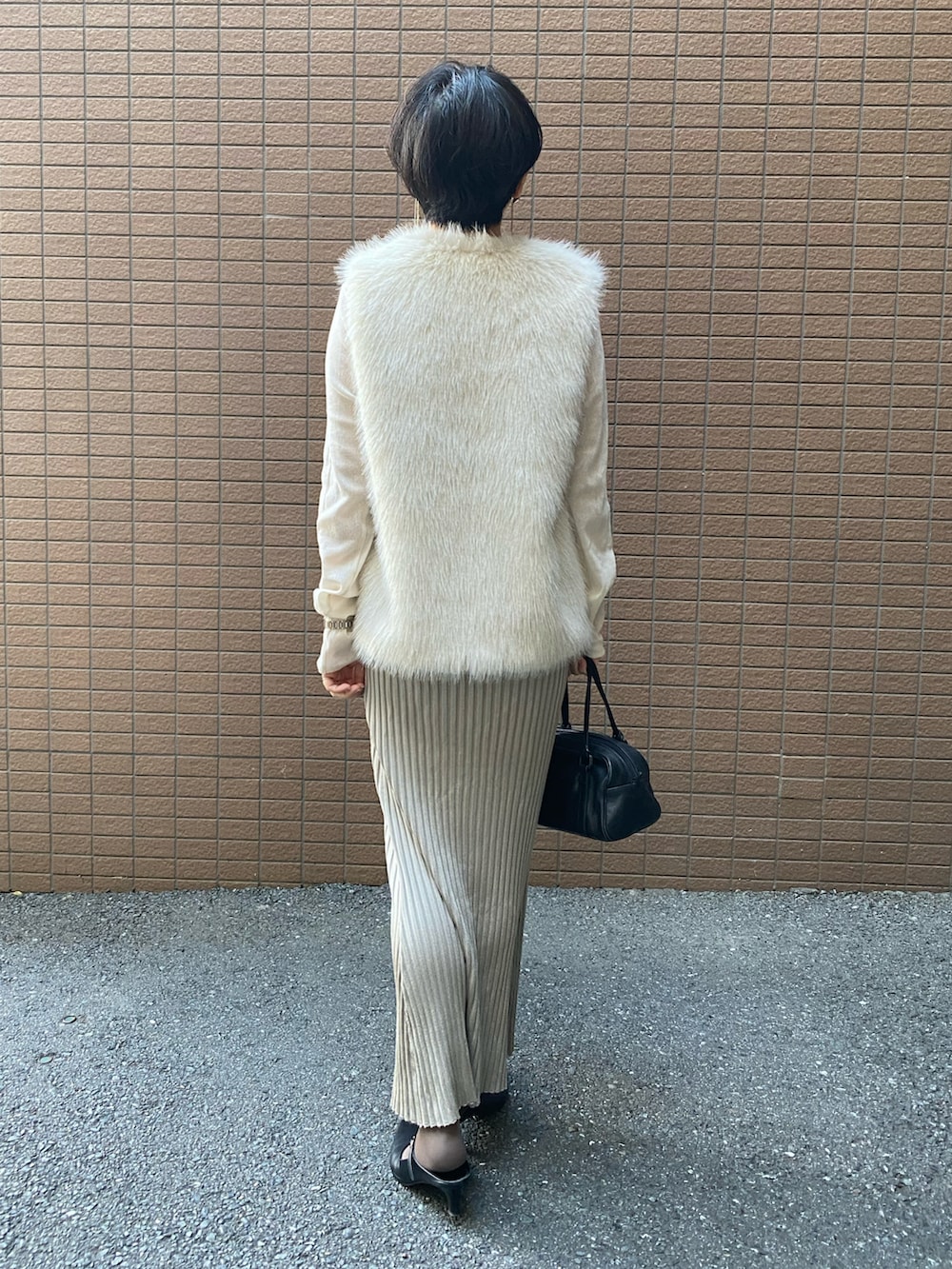 ホワイト系のベスト、ホワイト系のTシャツ/カットソー、ベージュ系のスカートを着用したレディースの秋コーディネートの3枚目の写真