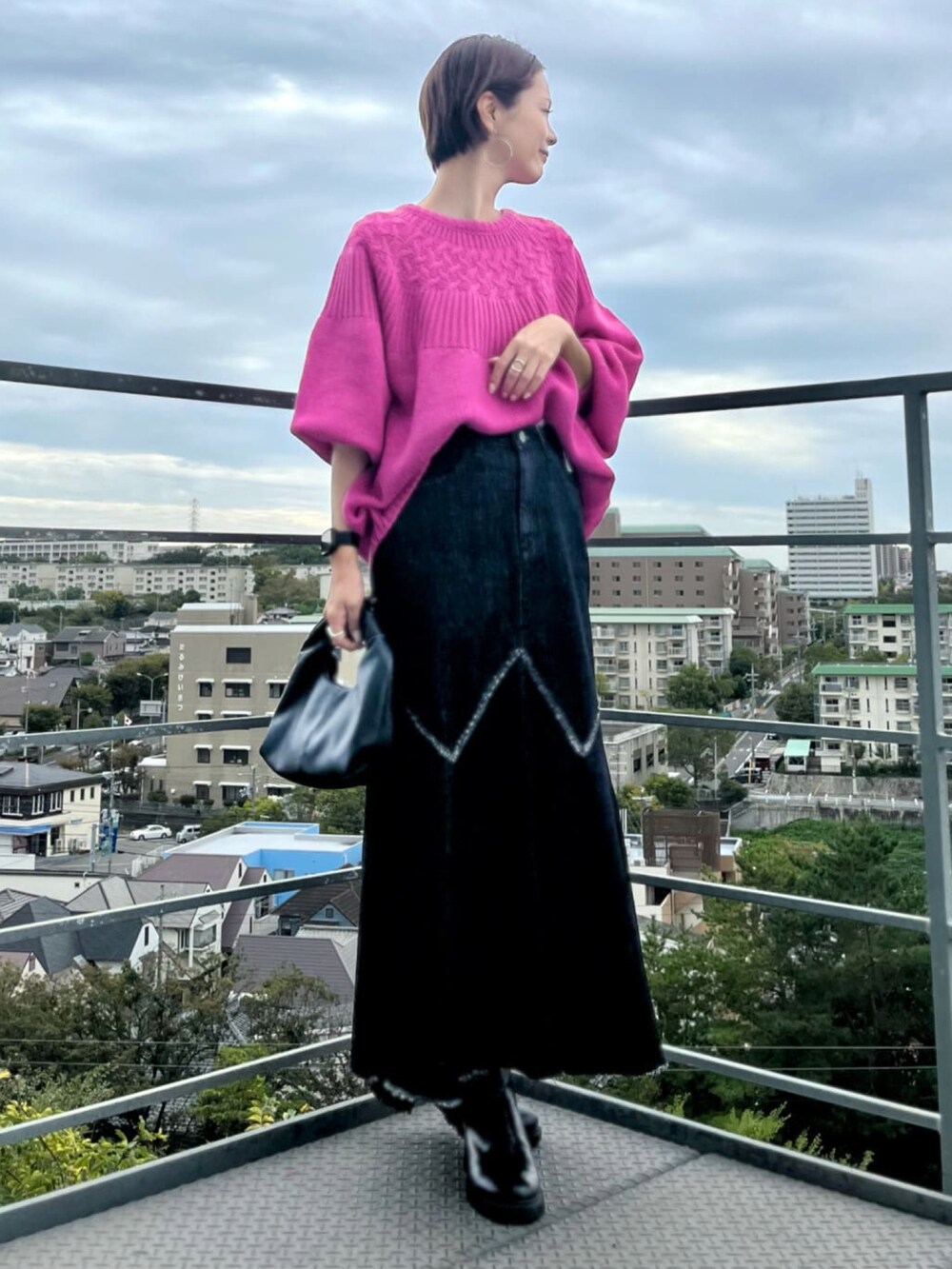 ブラック系のデニムスカート、ブラック系のハンドバッグ、ピンク系のニット/セーターを着用したレディースの秋コーディネートの5枚目の写真