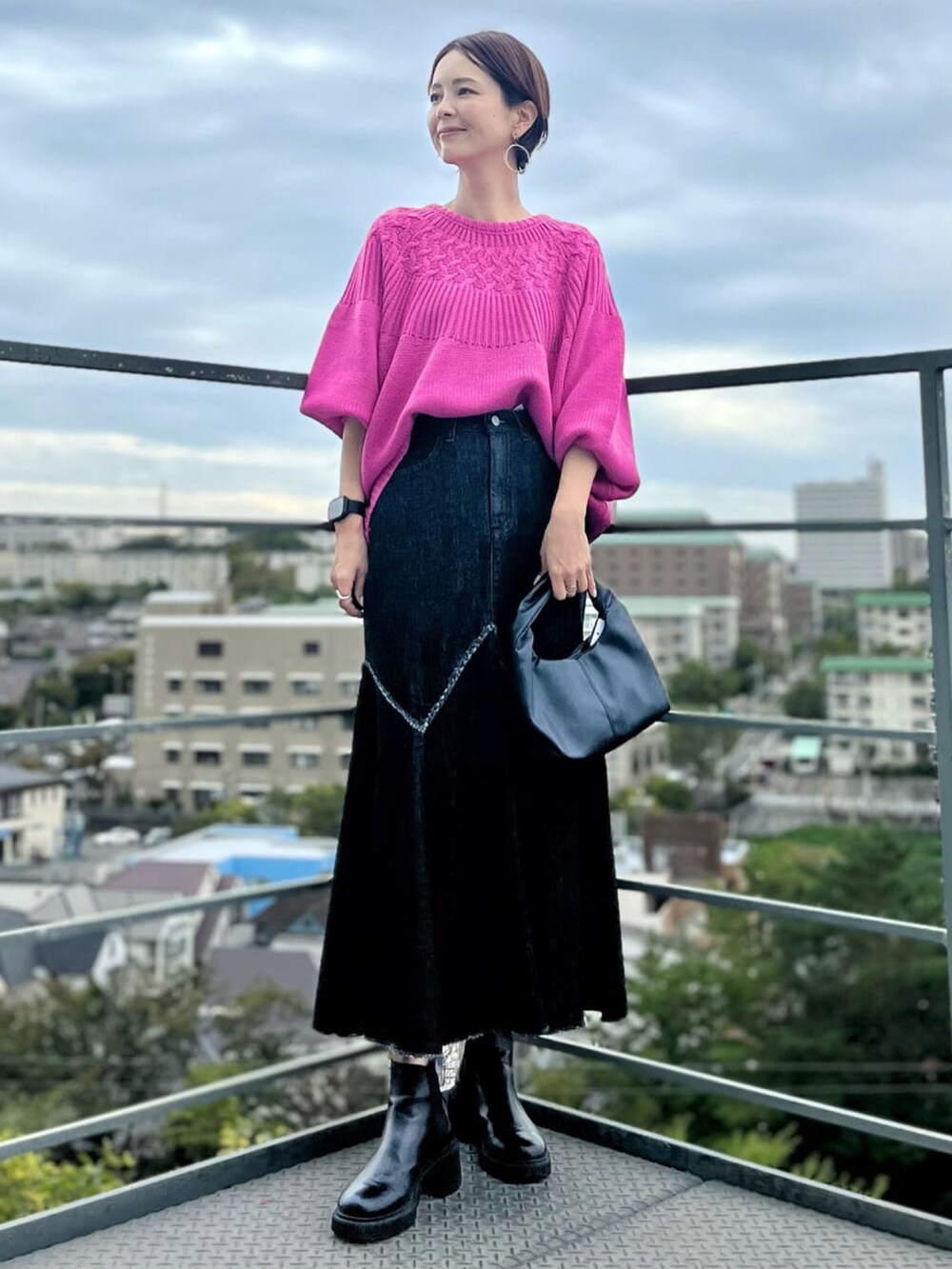 ブラック系のデニムスカート、ブラック系のハンドバッグ、ピンク系のニット/セーターを着用したレディースの秋コーディネートの3枚目の写真