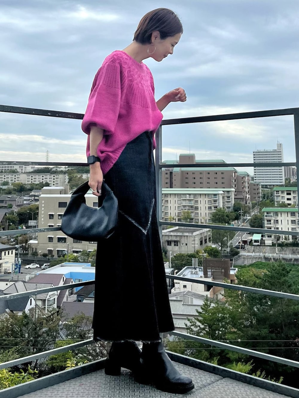 ブラック系のデニムスカート、ブラック系のハンドバッグ、ピンク系のニット/セーターを着用したレディースの秋コーディネートの4枚目の写真