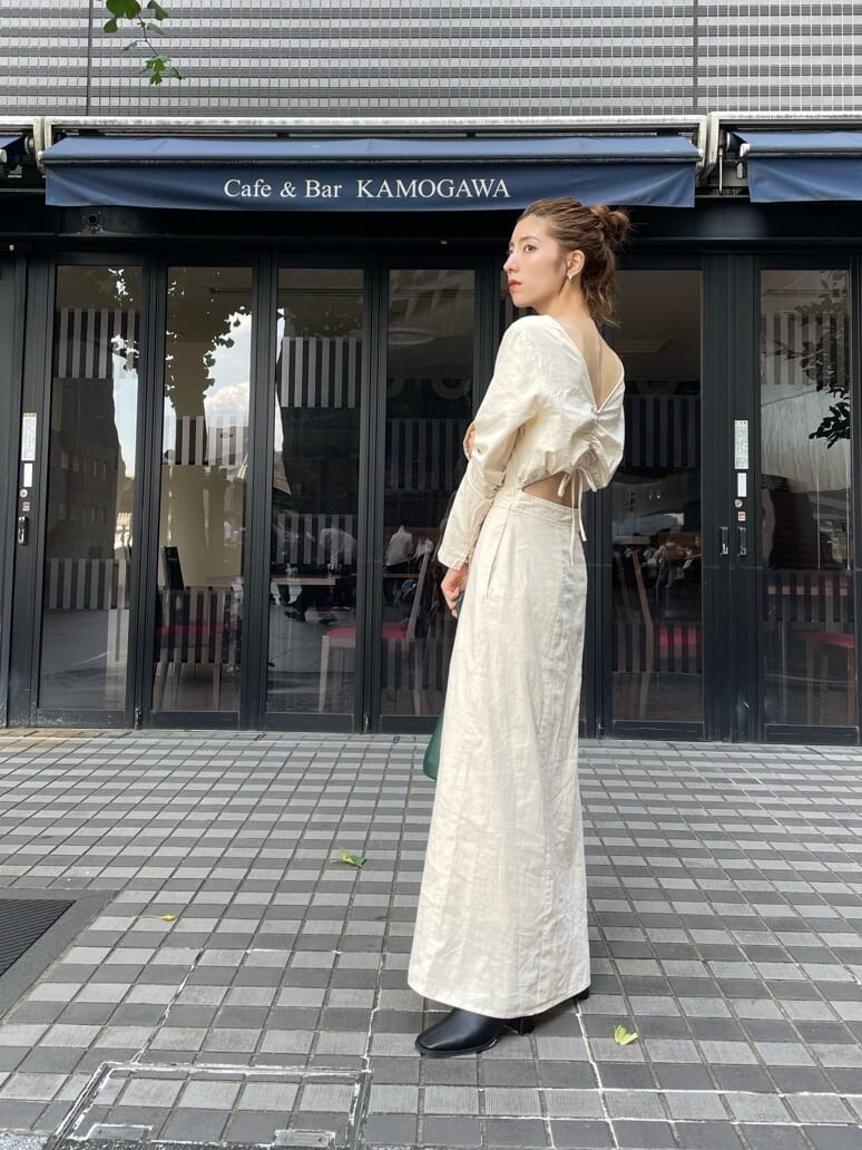 ブラック系のブーツ、グリーン系のハンドバッグ、ホワイト系のワンピースを着用したレディースの秋コーディネートの5枚目の写真