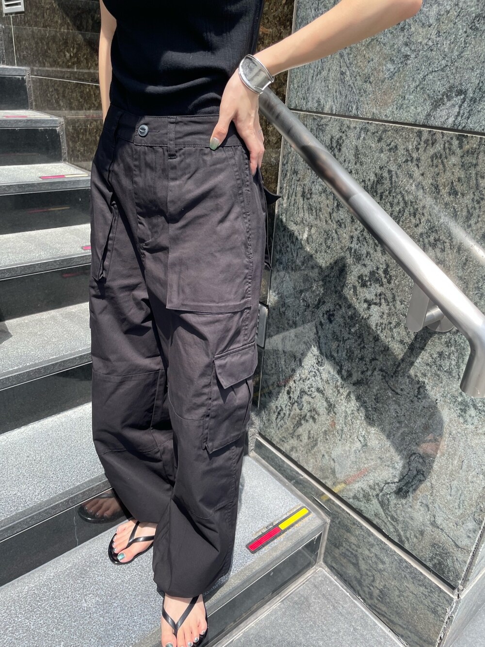 ブラック系のカーゴパンツ、ブラック系のタンクトップ、シルバー系のブレスレットを着用したレディースの夏コーディネートの5枚目の写真