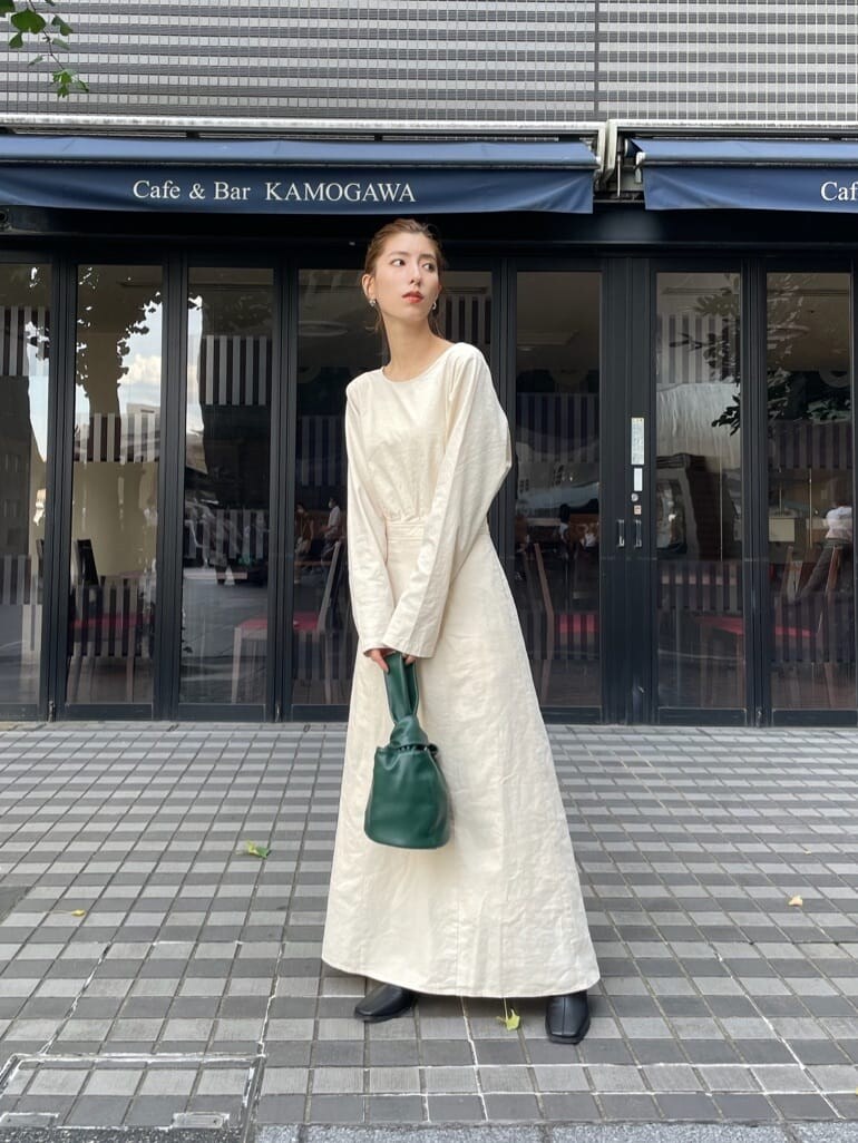 ブラック系のブーツ、グリーン系のハンドバッグ、ホワイト系のワンピースを着用したレディースの秋コーディネートの4枚目の写真