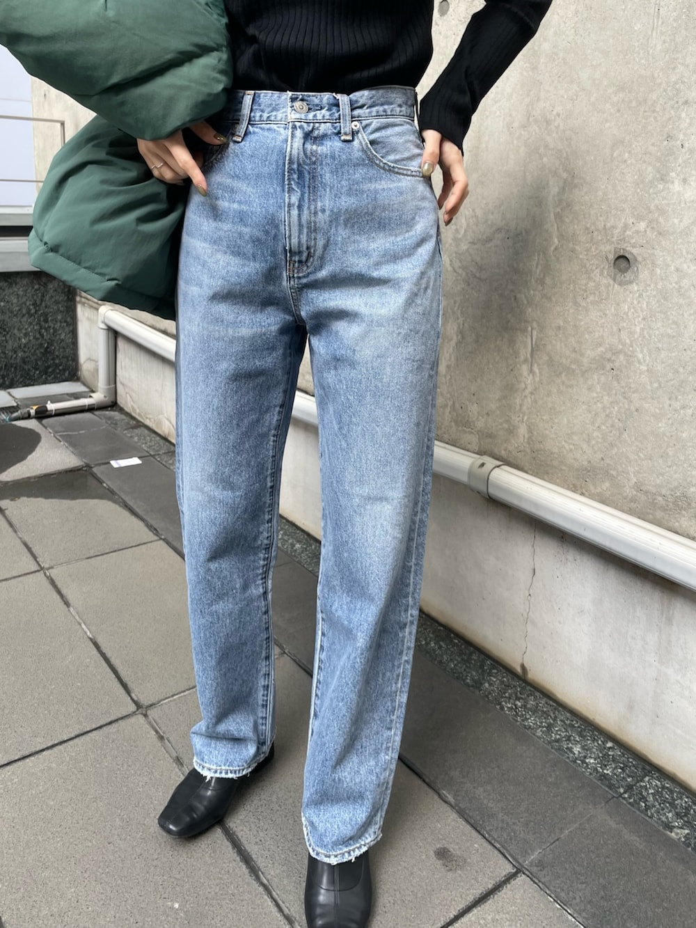 ブルー系のデニムパンツ、グリーン系のダウンジャケット/コート、ブラック系のニット/セーターを着用したレディースの秋コーディネートの4枚目の写真