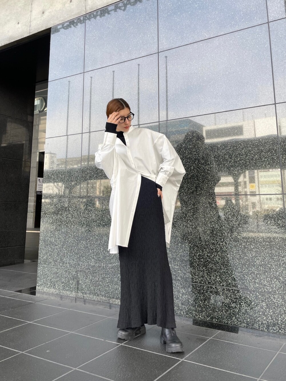 ブラック系のニット/セーター、ブラック系のスカート、ホワイト系のシャツ/ブラウスを着用したレディースの冬コーディネートの3枚目の写真