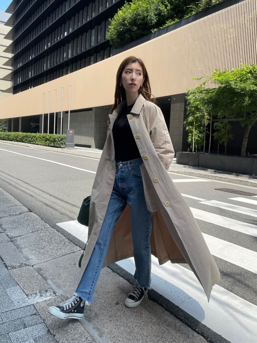 ベージュ系のステンカラーコート、ブラック系のニット/セーター、ブルー系のデニムパンツを着用したレディースの夏コーディネートの2枚目の写真