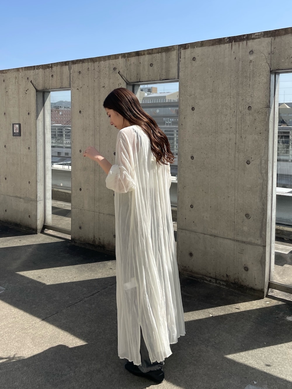 ホワイト系のワンピース、ホワイト系のタンクトップ、ブラック系のデニムパンツを着用したレディースの春コーディネートの4枚目の写真