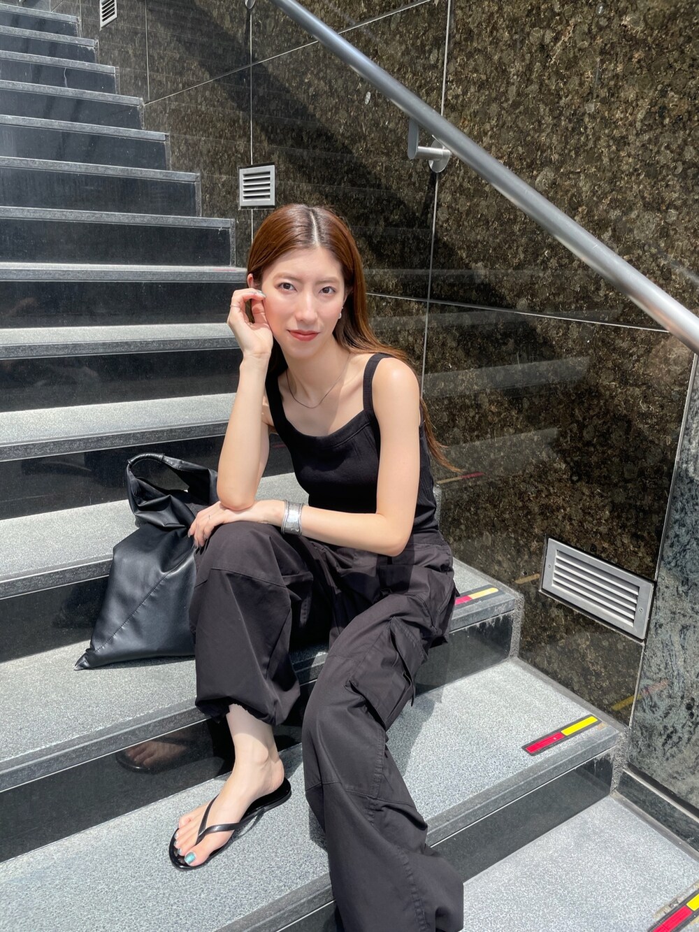 ブラック系のカーゴパンツ、ブラック系のタンクトップ、シルバー系のブレスレットを着用したレディースの夏コーディネートの3枚目の写真