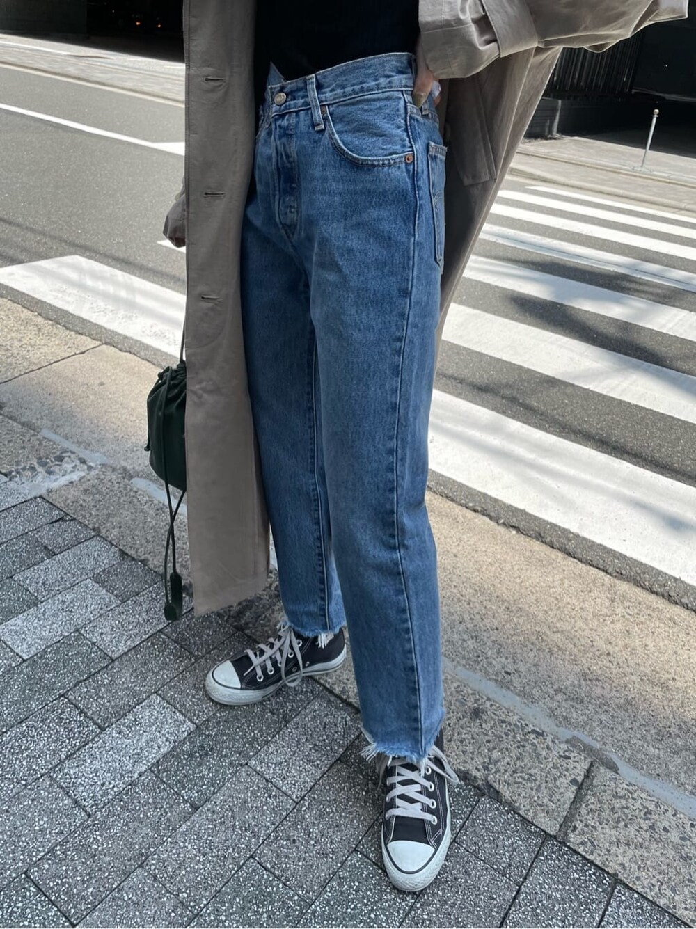 ベージュ系のステンカラーコート、ブラック系のニット/セーター、ブルー系のデニムパンツを着用したレディースの夏コーディネートの7枚目の写真