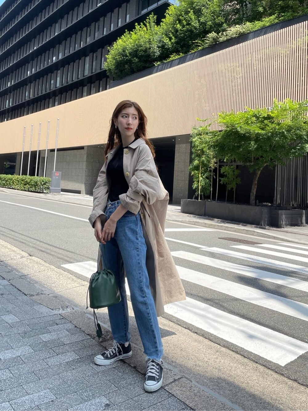 ベージュ系のステンカラーコート、ブラック系のニット/セーター、ブルー系のデニムパンツを着用したレディースの夏コーディネートの5枚目の写真