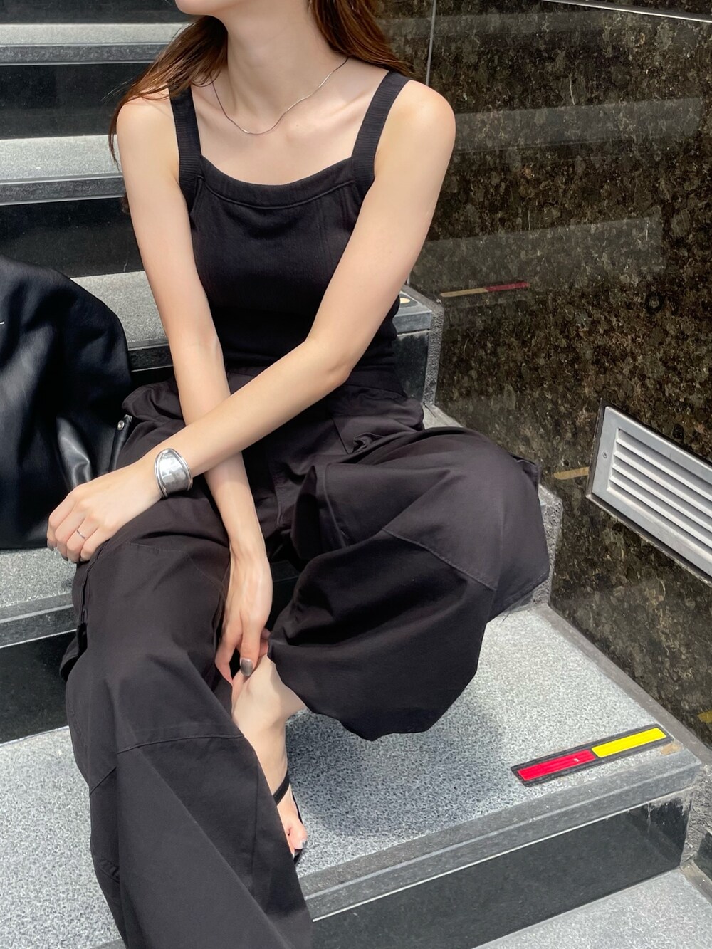 ブラック系のカーゴパンツ、ブラック系のタンクトップ、シルバー系のブレスレットを着用したレディースの夏コーディネートの4枚目の写真