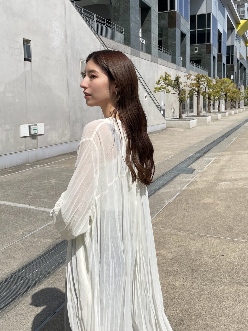 ホワイト系のワンピース、ホワイト系のタンクトップ、ブラック系のデニムパンツを着用したレディースの春コーディネートの2枚目の写真