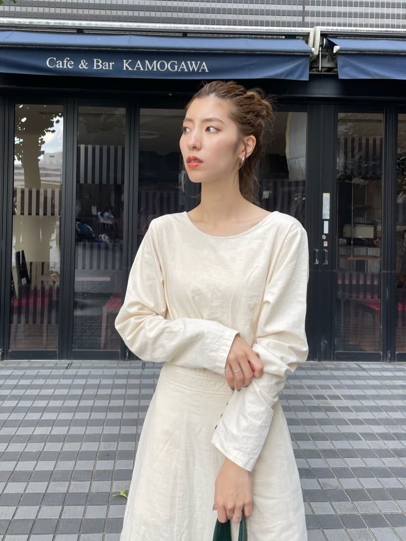 ブラック系のブーツ、グリーン系のハンドバッグ、ホワイト系のワンピースを着用したレディースの秋コーディネートの2枚目の写真