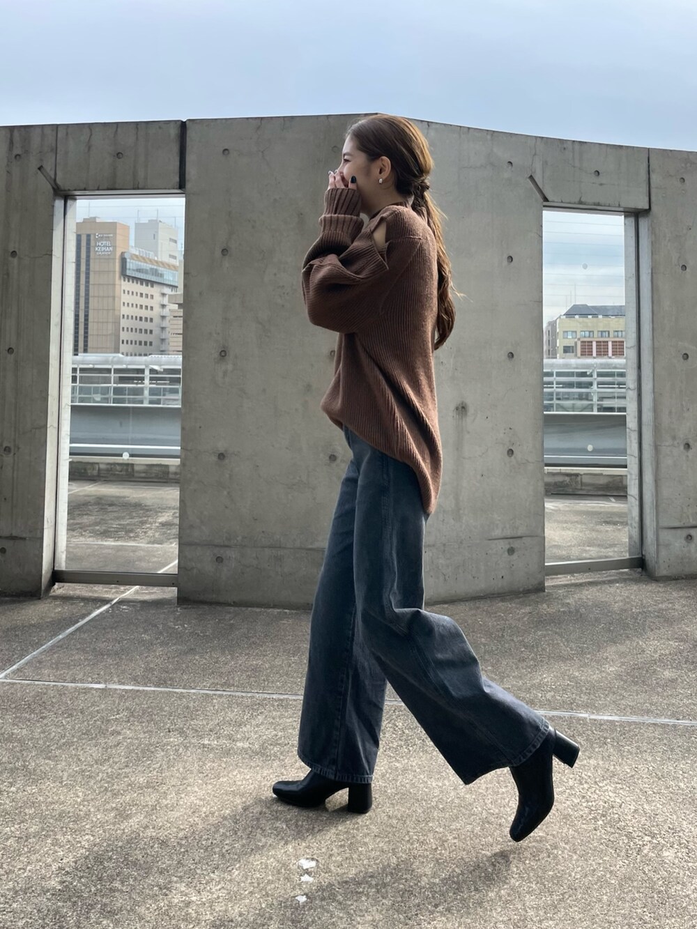 ブラウン系のニット/セーター、ブラック系のデニムパンツ、ホワイト系のハンドバッグを着用したレディースの秋コーディネートの4枚目の写真