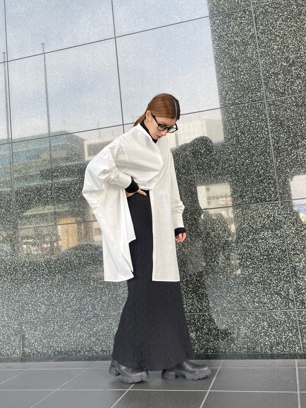 ブラック系のニット/セーター、ブラック系のスカート、ホワイト系のシャツ/ブラウスを着用したレディースの冬コーディネートの2枚目の写真