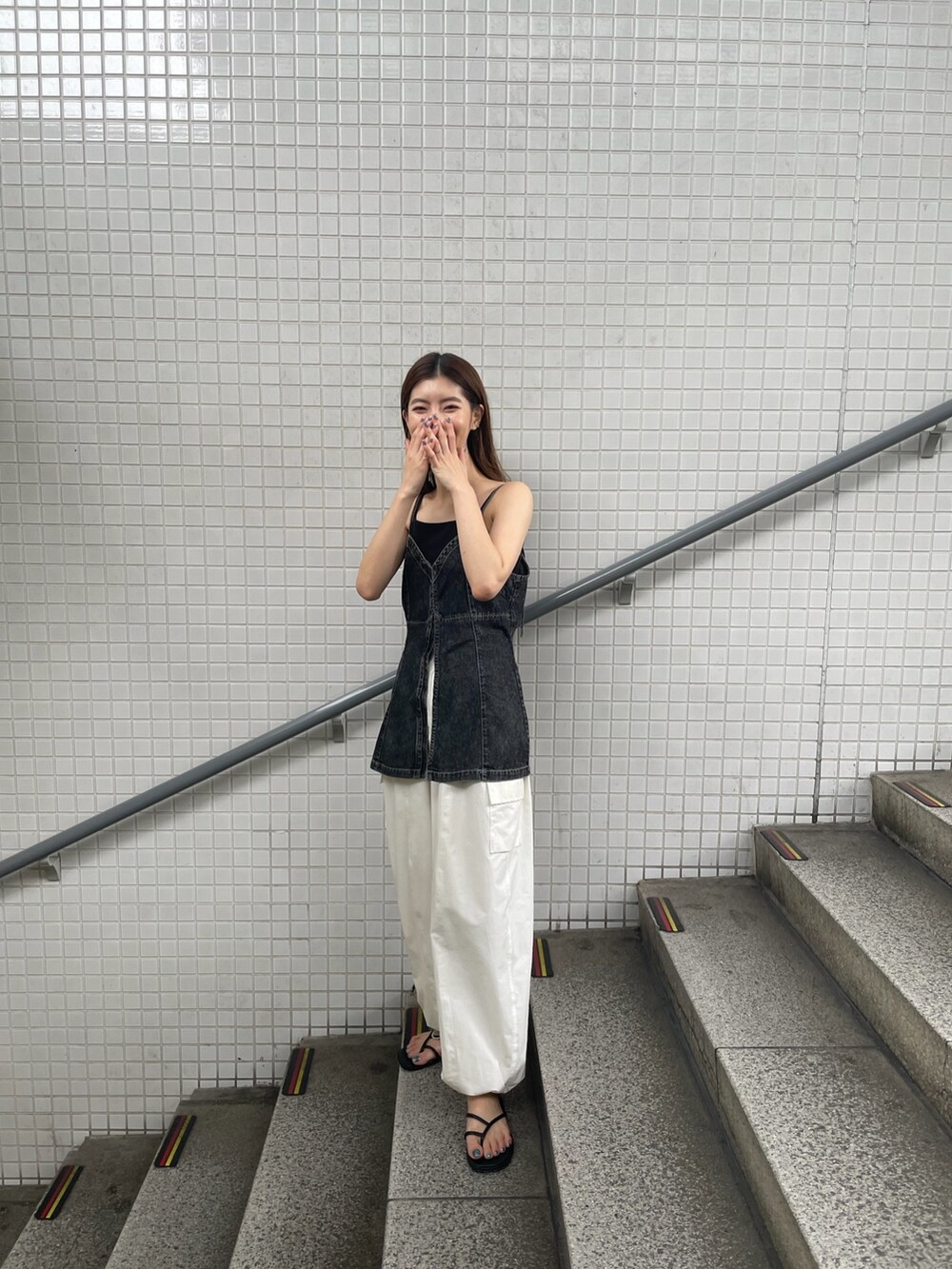 ブラック系のキャミソール、ホワイト系のカーゴパンツを着用したレディースの夏コーディネートの3枚目の写真