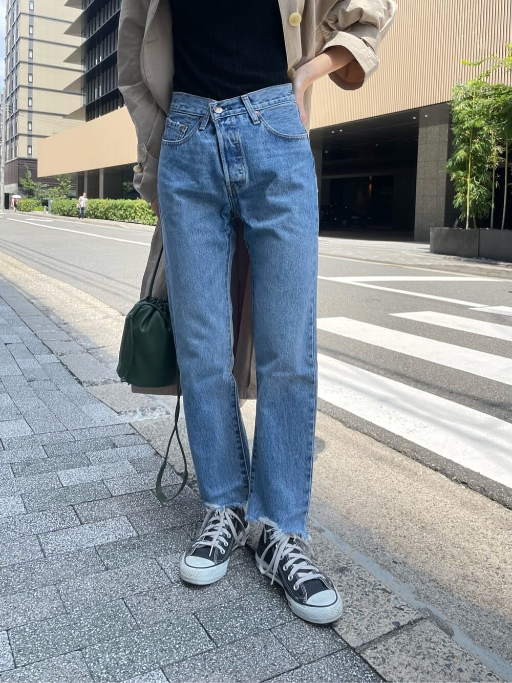 ベージュ系のステンカラーコート、ブラック系のニット/セーター、ブルー系のデニムパンツを着用したレディースの夏コーディネートの6枚目の写真