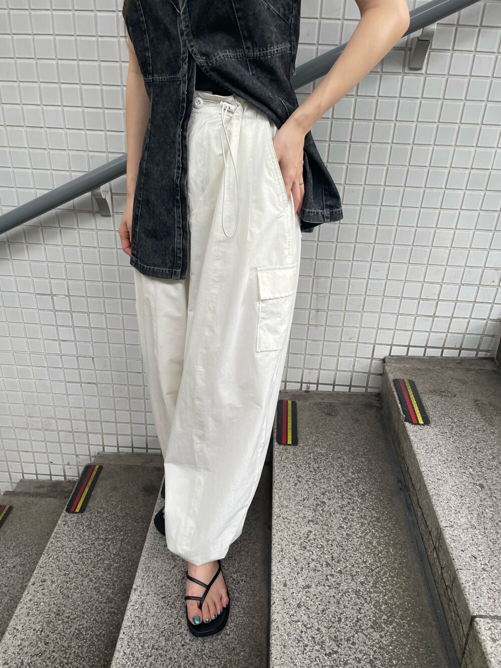 ブラック系のキャミソール、ホワイト系のカーゴパンツを着用したレディースの夏コーディネートの4枚目の写真