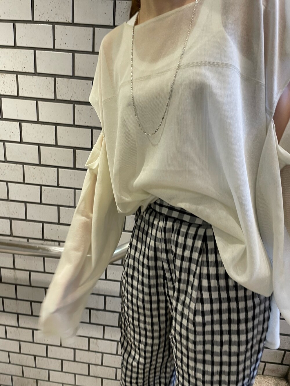 イエロー系のニット/セーター、ホワイト系のタンクトップ、グレー系のその他パンツを着用したレディースの冬コーディネートの3枚目の写真