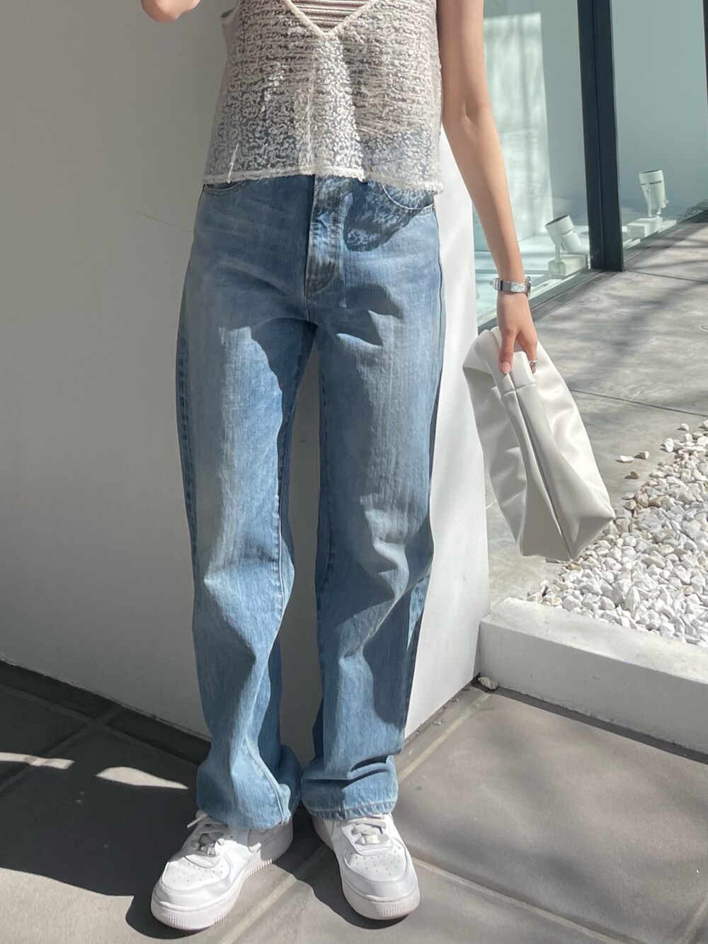 ホワイト系のハンドバッグ、ブルー系のデニムパンツ、ホワイト系のキャミソールを着用したレディースの春コーディネートの6枚目の写真