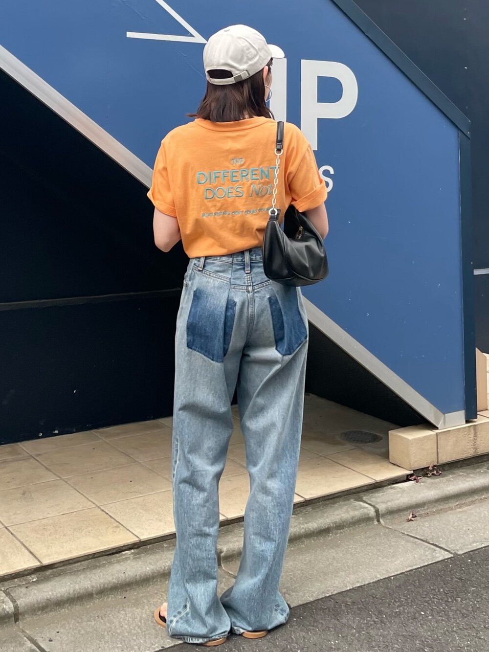 ブラック系のサンダル、ブルー系のデニムパンツ、オレンジ系のTシャツ/カットソーを着用したレディースの夏コーディネートの3枚目の写真