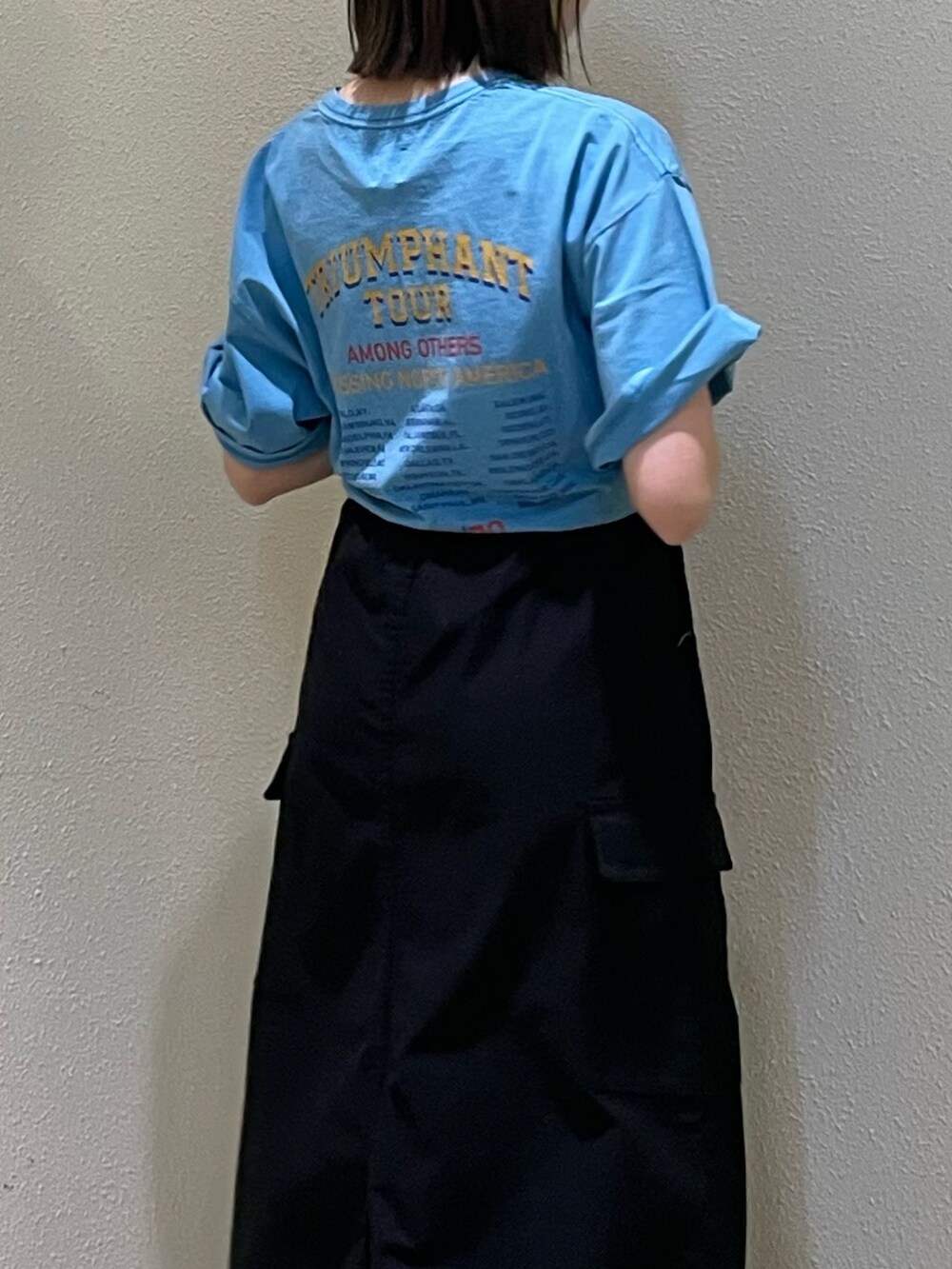 ブルー系のTシャツ/カットソー、ブラック系のスカート、ゴールド系のネックレスを着用したレディースの春コーディネートの6枚目の写真