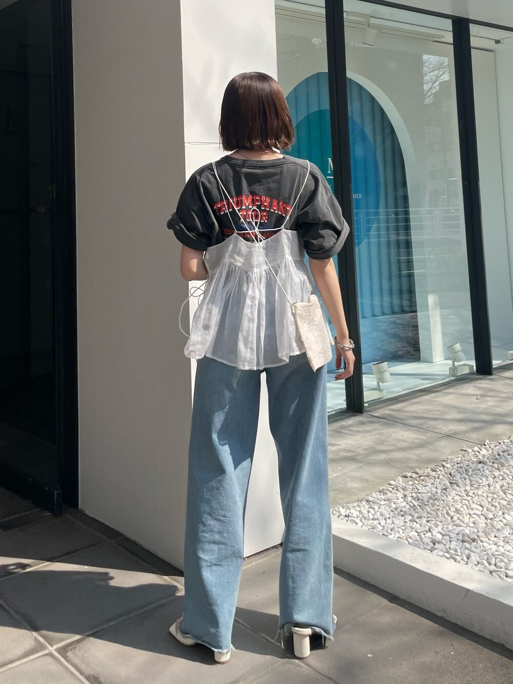 ブルー系のデニムパンツ、グレー系のTシャツ/カットソー、ホワイト系のショルダーバッグを着用したレディースの春コーディネートの3枚目の写真