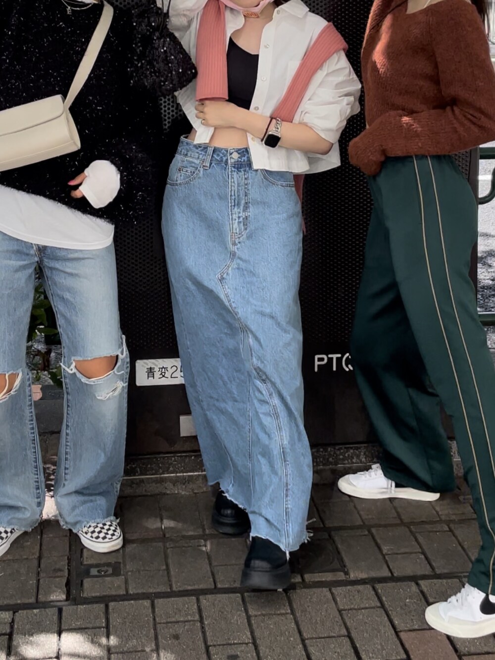 ブラック系のブーツ、ブルー系のデニムスカート、ブラック系のハンドバッグを着用したレディースの秋コーディネートの4枚目の写真