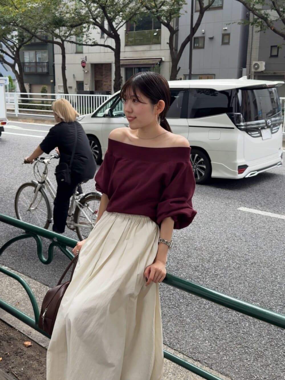 ブラウン系のハンドバッグ、ホワイト系のスカート、レッド系のスウェットを着用したレディースの秋コーディネートの6枚目の写真