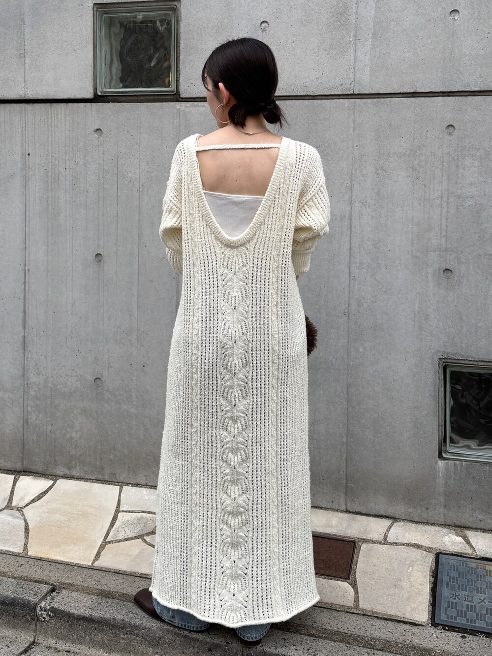 ホワイト系のワンピース、ブルー系のデニムパンツ、ブラウン系のブーツを着用したレディースの冬コーディネートの5枚目の写真