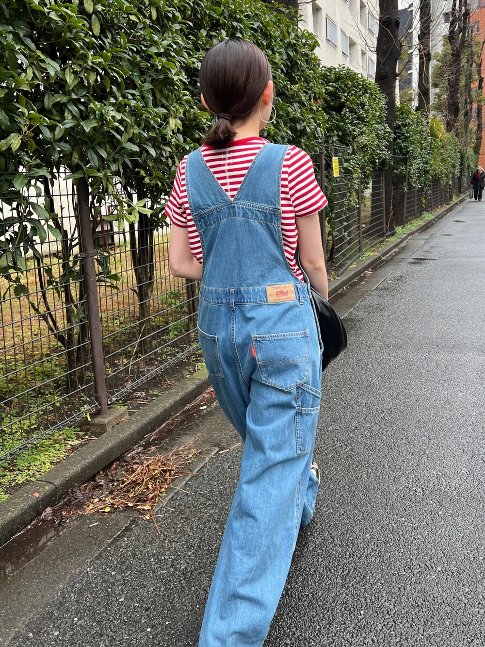 ブラック系のサンダル、ブルー系のつなぎ/オールインワン、レッド系のTシャツ/カットソーを着用したレディースの春コーディネートの5枚目の写真