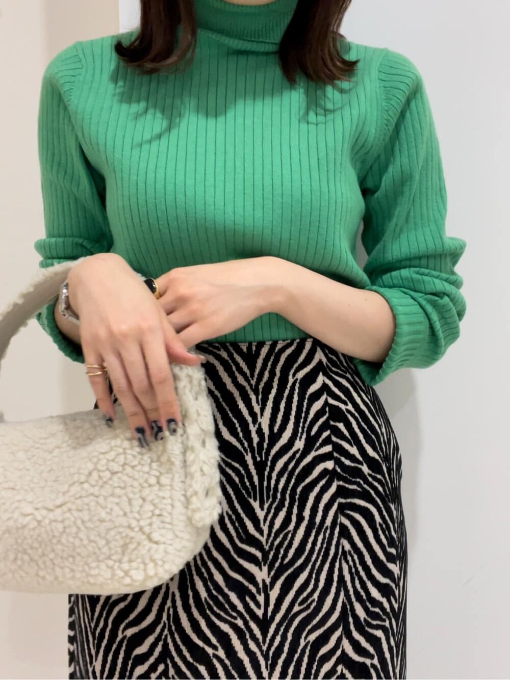 ホワイト系のハンドバッグ、グリーン系のニット/セーター、ブラック系のスカートを着用したレディースの秋コーディネートの2枚目の写真