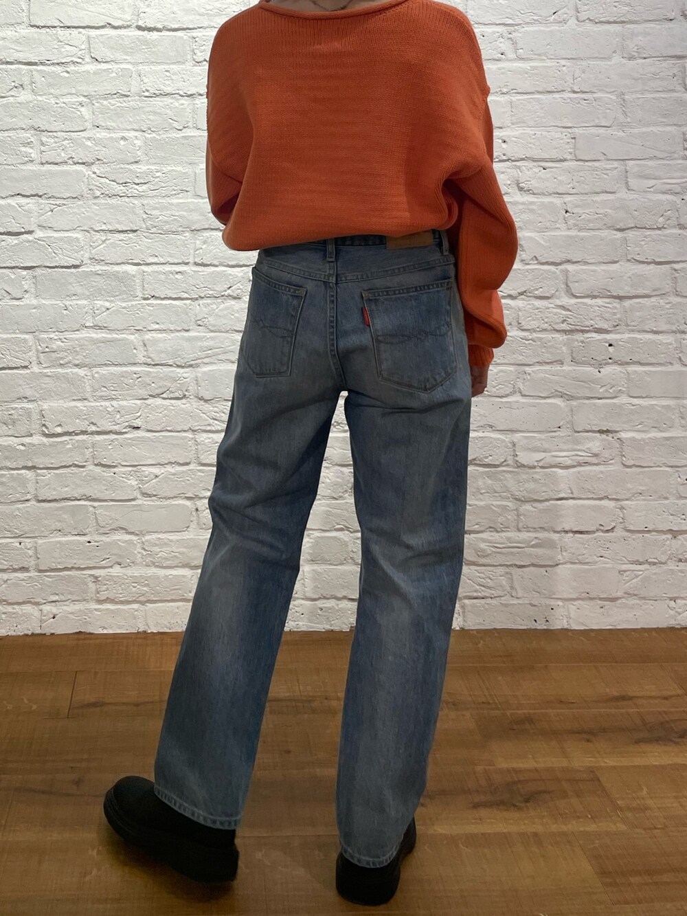 オレンジ系のニット/セーター、ブルー系のデニムパンツ、ブラック系のブーツを着用したレディースの冬コーディネートの4枚目の写真