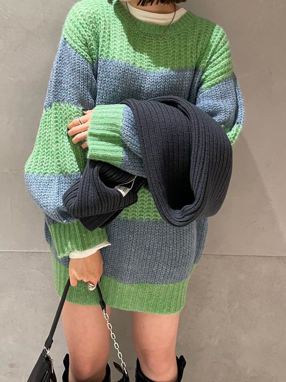 グリーン系のニット/セーター、ホワイト系のTシャツ/カットソー、グレー系のマフラーを着用したレディースの冬コーディネートの5枚目の写真