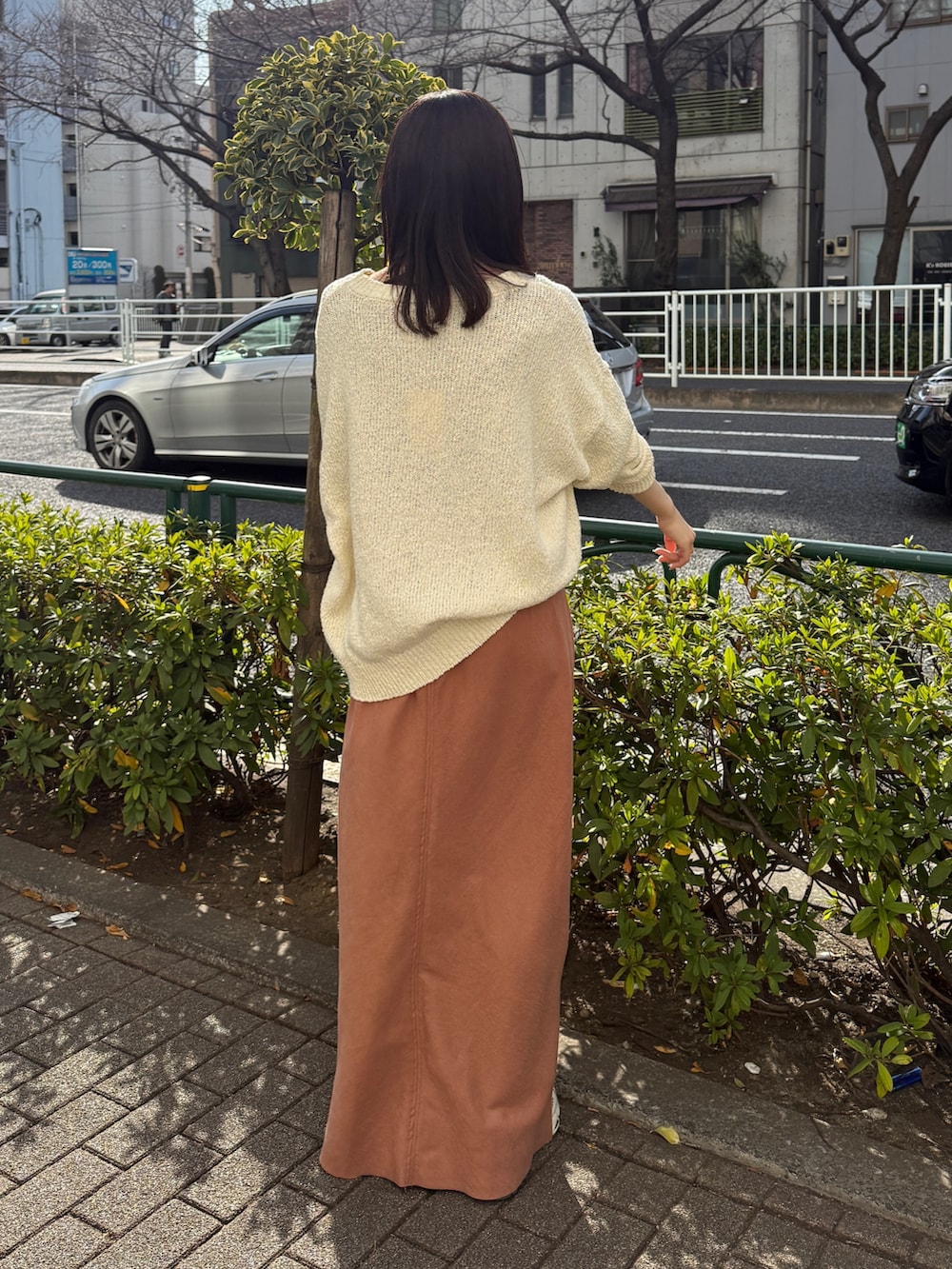 オレンジ系のスカート、ホワイト系のニット/セーターを着用したレディースの冬コーディネートの5枚目の写真