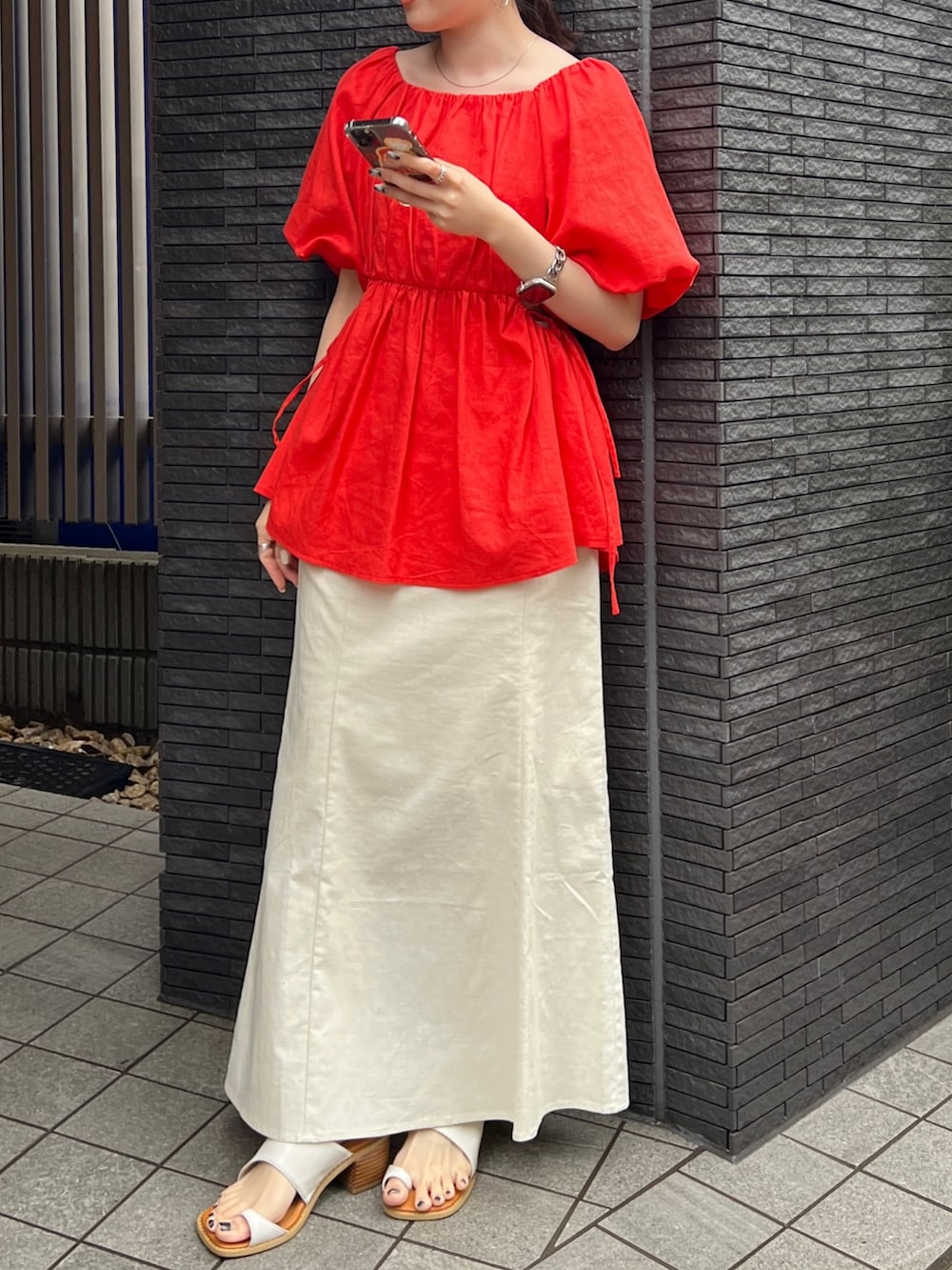 グレー系のキャミソール、ホワイト系のスカート、ホワイト系のサンダルを着用したレディースの春コーディネートの2枚目の写真