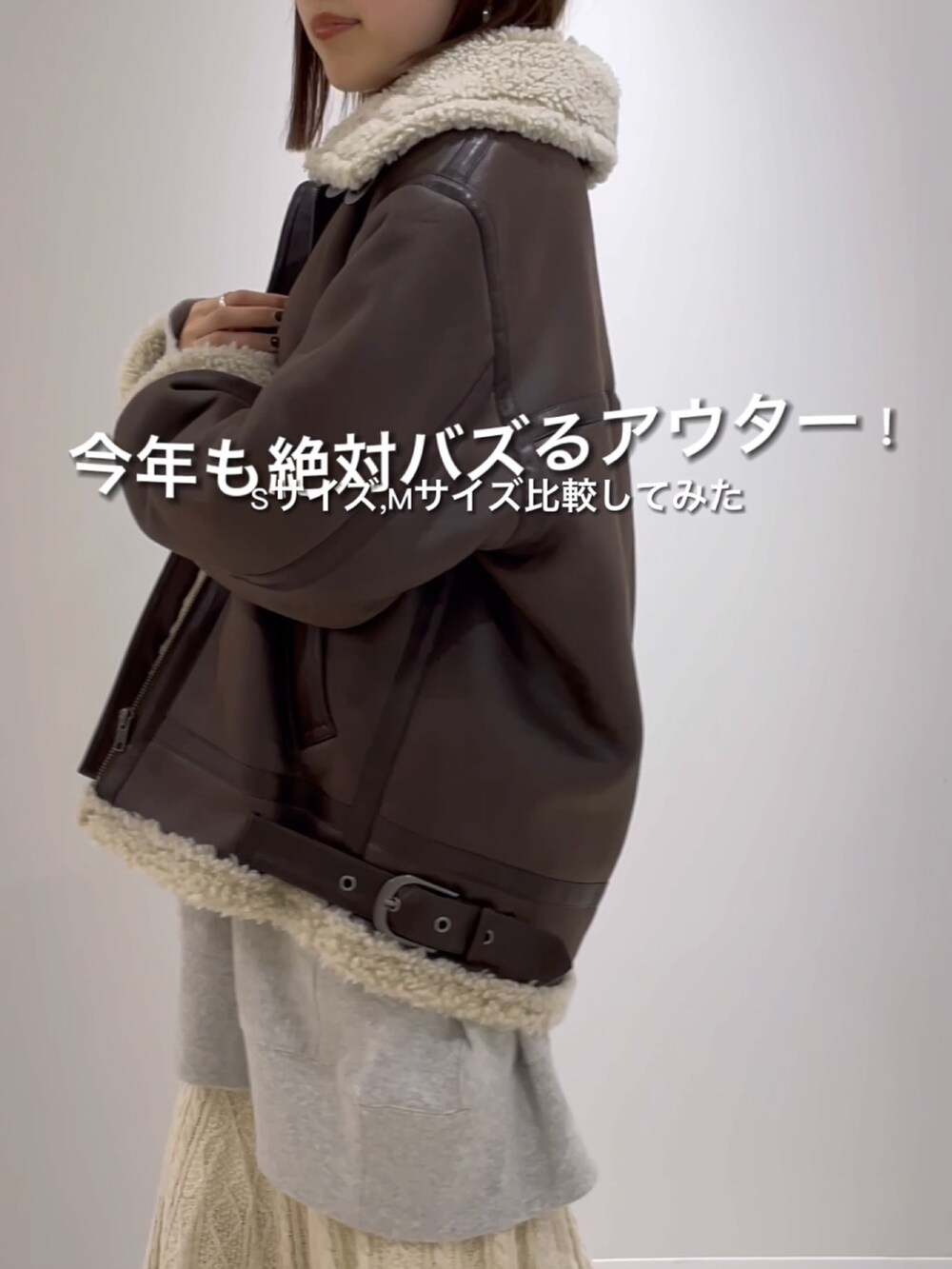 ブラウン系のムートンコート、グレー系のスウェット、ホワイト系のスカートを着用したレディースの秋コーディネートの3枚目の写真