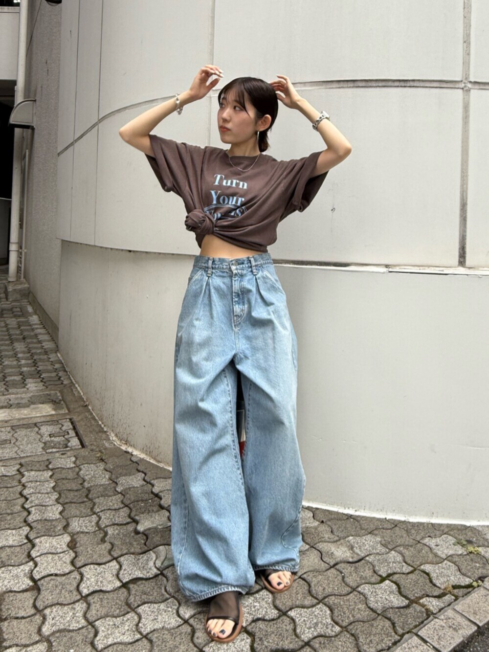 ブラック系のサンダル、ブルー系のデニムパンツ、ブラウン系のTシャツ/カットソーを着用したレディースの夏コーディネートの4枚目の写真