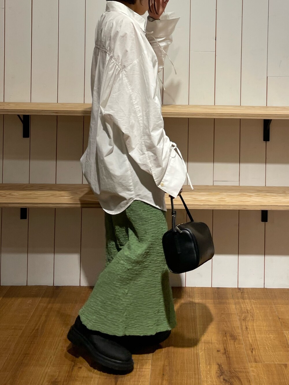 ブラック系のハンドバッグ、ブラック系のブーツ、ホワイト系のシャツ/ブラウスを着用したレディースの冬コーディネートの2枚目の写真