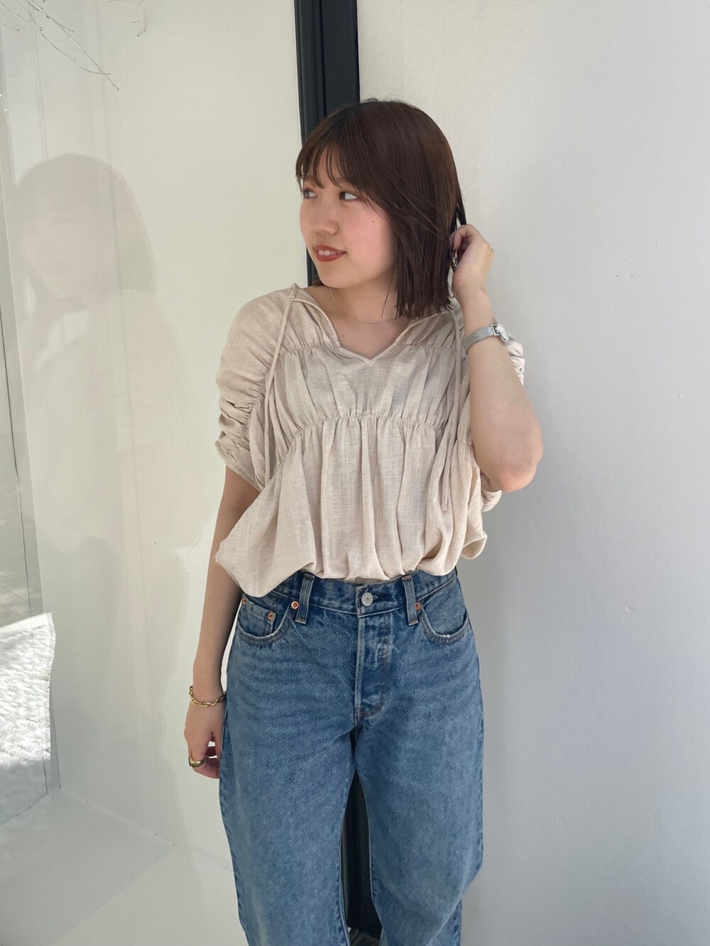 ホワイト系のシャツ/ブラウス、ブラック系のスニーカー、ブルー系のデニムパンツを着用したレディースの夏コーディネートの2枚目の写真