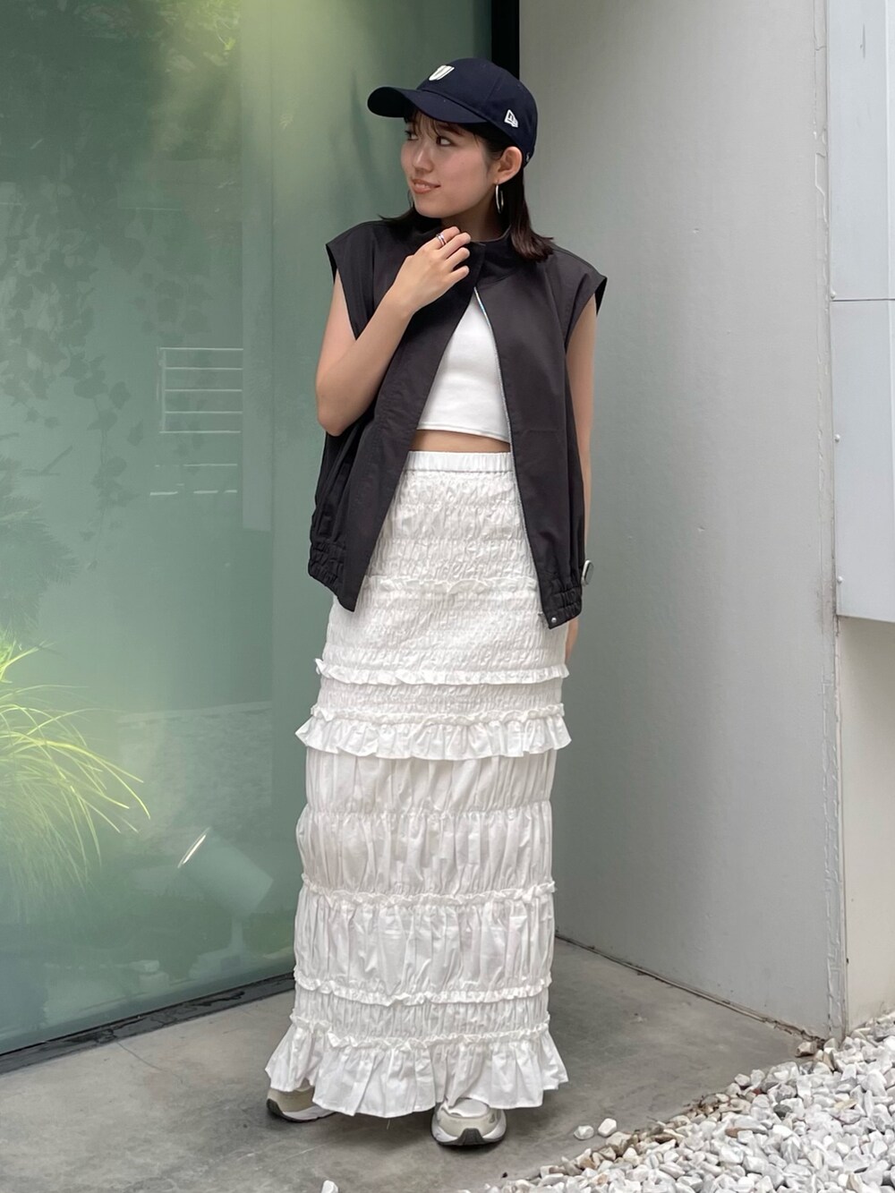 グレー系のベスト、ホワイト系のスカート、ブルー系のキャップを着用したレディースの夏コーディネートの6枚目の写真