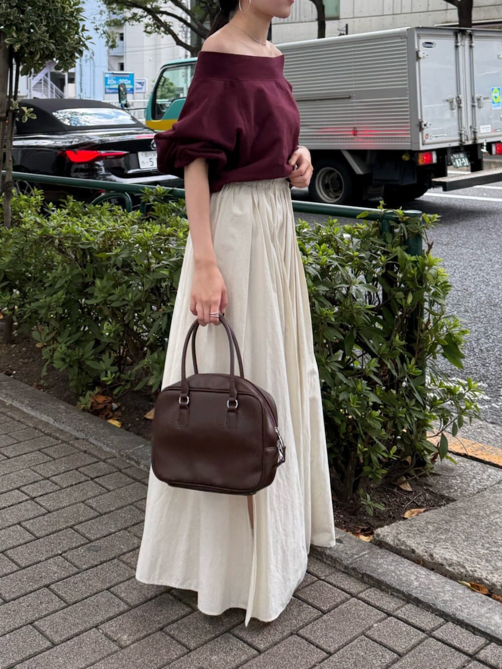 ブラウン系のハンドバッグ、ホワイト系のスカート、レッド系のスウェットを着用したレディースの秋コーディネートの2枚目の写真