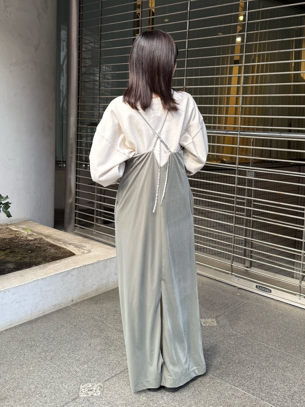 グレー系のワンピース、ホワイト系のスウェット、ブラック系のブーツを着用したレディースの冬コーディネートの4枚目の写真