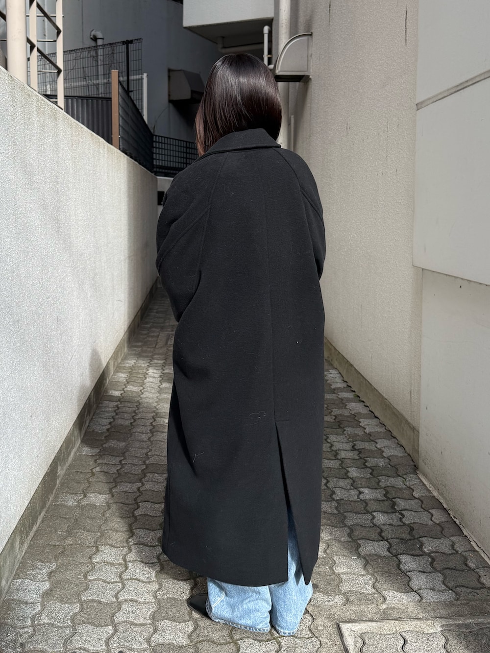 ブルー系のデニムパンツ、ブラック系のブーツ、ブラック系のチェスターコートを着用したレディースの冬コーディネートの3枚目の写真